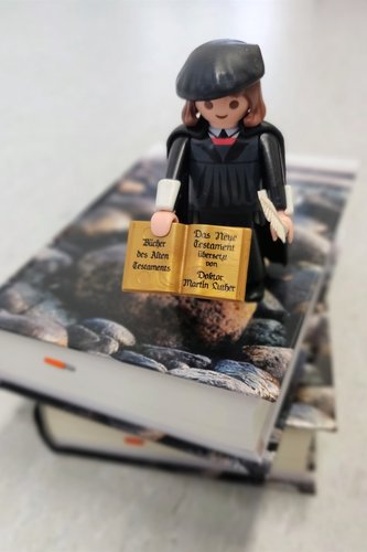 Martti Luther playmobil -hahmo on raamattupinon päällä.