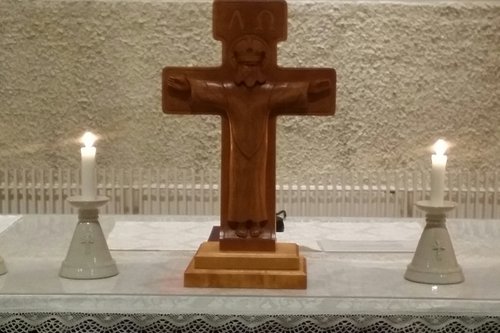 Kuva kirkon alttarista, jolla on kynttilöitä ja risti